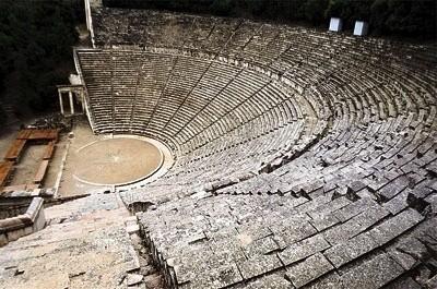 Κάτω και μπροστά στη σκηνή είναι η ορχήστρα, ένας χώρος ημικυκλικός, που κινούνται οι χορευτές (τα μέλη του χορού). Δεξιά και αριστερά βλέπουμε εισόδους απ έξω προς την ορχήστρα.