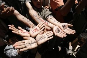 Αντικαθεστωτικοί διαδηλωτές δείχνουν συνθήματα που έχουν γράψει στα χέρια τους, στα αραβικά και στα αγγλικά, κατά τη διάρκεια διαδήλωσης στην Κεντρική Σαναά τη Δευτέρα, ζητώντας την απομάκρυνση του