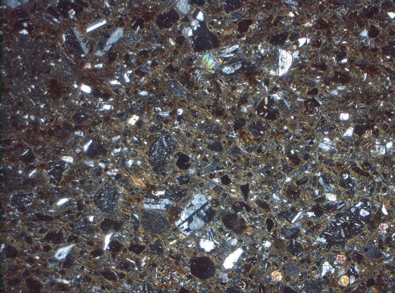 3: Φωτογραφία λεπτής τομής κεραμικής ύλης Γ, χαμηλά ασβεστιούχος με θραύσματα μεταμορφωμένων πετρωμάτων που έχουν προέλθει από όξινα πλουτώνια (25x, XP, εύρος πεδίου 5.5mm). Εικ.