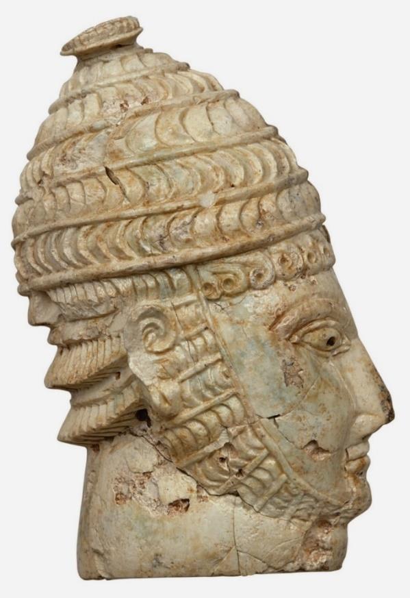 Scolpita nell'avorio, a tutto tondo, questa scultura rappresenta la testa di un guerriero che indossa un elmo fatto con denti di cinghiale. Risalente al 1300 a.c. e ritrovata presso Micene è attualmente conservata al Museo Archeologico Nazionale di Atene.