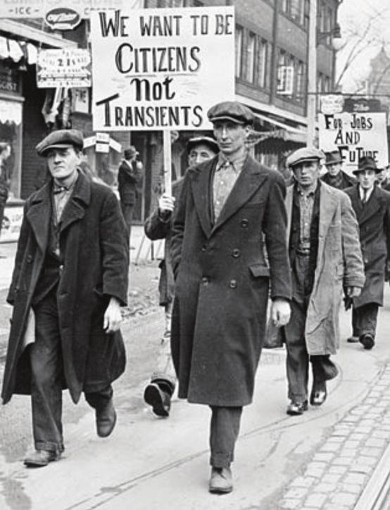 Οικονομική κρίση του 1929. Διαδήλωση ανέργων στον Καναδά. Το πλακάτ που κρατάει ο διαδηλωτής γράφει: «Θέλουμε να είμαστε πολίτες και όχι περαστικοί».