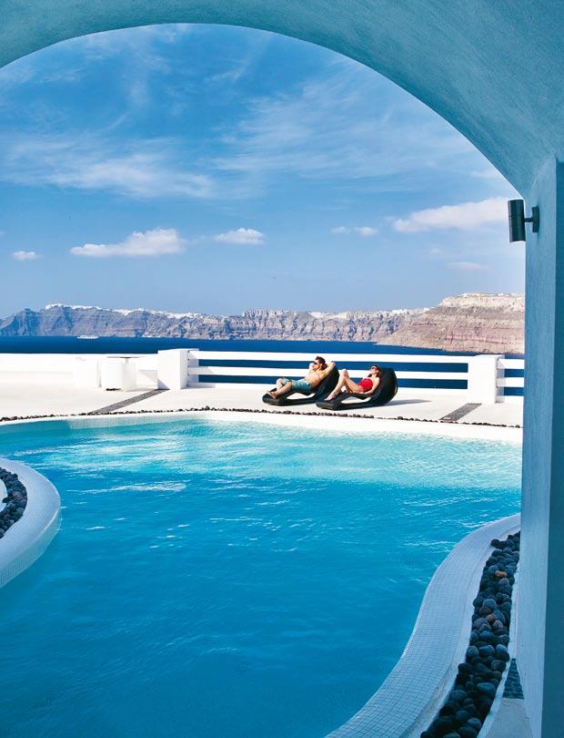 Thira s awesome, steep volcanic rocks form a surreal background to the idyllic pool of the sun-drenched Avant Garde Suites Ready for a night