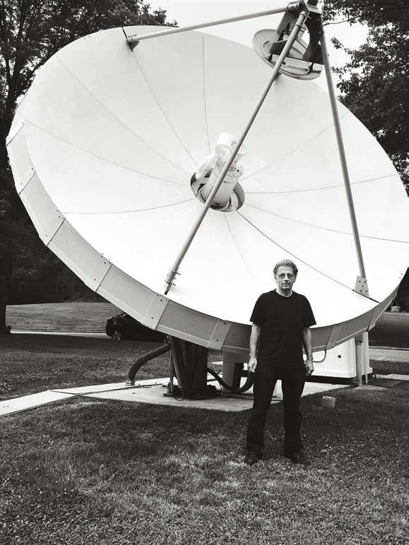 O δρ Ματσάκης μπροστά από ένα δορυφορικό κάτοπτρο, που αποτελεί βασικό εξάρτημα ενός δορυφορικού συστήματος μέσα στο χώρο του πανεπιστημίου.