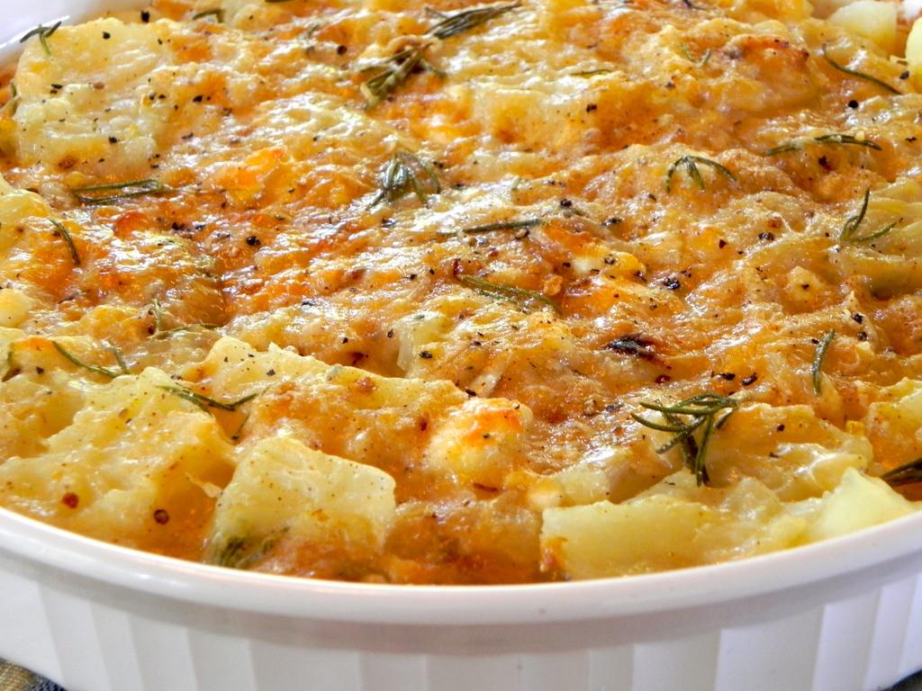 Πατάτες au gratin 2 αυγά 150 γρ. τριμμένη γραβιέρα 1 κουταλάκι κάρυ 200 γρ. φιλέτο κοτόπουλο κομμένο σε κύβους 1 πρέζα μοσχοκάρυδο 5 μετρίου μεγέθους πατάτες άσπρο πιπέρι 2 κύβοι μυρωδικών 150 γρ.