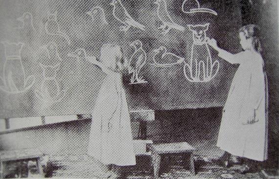 Εικόνα 1: Φωτογραφία τάξης από τα τέλη του 19ου αιώνα στην οποία μικρά παιδιά αντιγράφουν σχέδια του δασκάλου στον μαυροπίνακα.