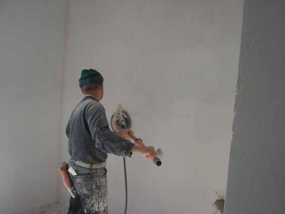 Λείανση του τοίχου από εργάτη ο οποίος δεν χρησιμοποιεί μάσκα
