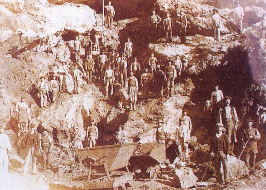 Στο πλάτωμα της σκάλας μπροστά στις στοές, ανάμεσα στα βαγόνια είναι συγκεντρωμένο πλήθος από 400 μεταλλωρύχους και 1000 γυναικόπαιδα. Το απόσπασμα με «εφ όπλου λόγχη» παρατάσσεται στην αποβάθρα.