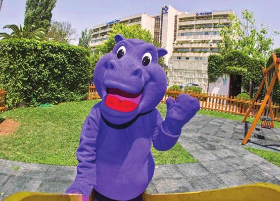 Ένας χαρούμενος μωβ ιπποπόταμος μασκότ απασχολεί δημιουργικά τους μικρούς ασθενείς μας, παίζοντας και μαθαίνοντάς τους όλα όσα χρειάζονται για τους κανόνες προσωπικής υγιεινής, ενώ παράλληλα τους