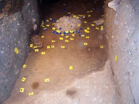 Σπήλαιο «Θεόπετρας» Θεσσαλίας Σκάμμα Λ10-Μ10,, κοντά στα ανατολικά τοιχώματα κατά την ανασκαφή. Πάνω σε μπλε καρτελάκια διακρίνονται τα ευρεθέντα οστά και σε κίτρινα τα λίθινα εργαλεία.