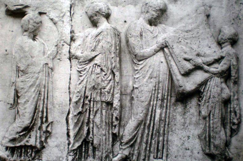 Ιωνική ζωφόρος του Παρθενώνος. Μορφές από την κεντρική σκηνή της ανατολικής πλευράς. Μία Αρρηφόρος παραδίδει ενδύματα (;) που μεταφέρει πάνω σε δίφρο στην ιέρεια της Αθηνάς Πολιάδος.