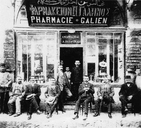 Φαρμακείο «Γαληνός» του Αναστασίου Μπαμπασίκα το 1910 στην οδό Μητροπόλεως. Όρθιος αριστερά ο φαρμακοποιός. Δίπλα του ο νεαρός Γ.